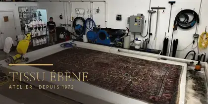 Grand tapis persan étendu sur la table de lavage de l&rsquo;atelier Tissu Ébène, en région parisienne