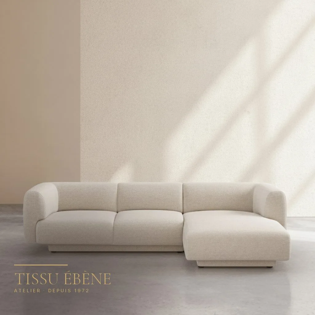 Canapé d&rsquo;angle en tissu bouclé crème aux formes arrondies devant un mur clair
