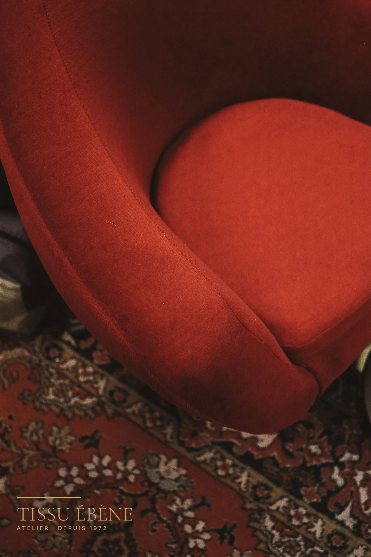 Assise et accotoir arrondis d'un petit fauteuil crapaud en velours rouge