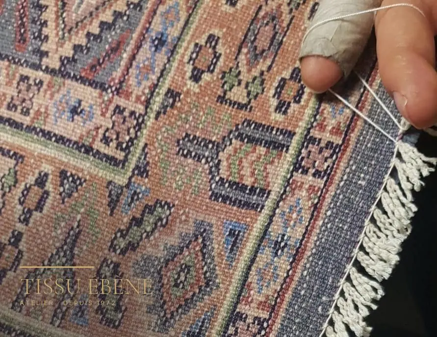 Expertise de tapis : examen du revers d’un tapis noué main, où se lisent la densité et les reprises anciennes