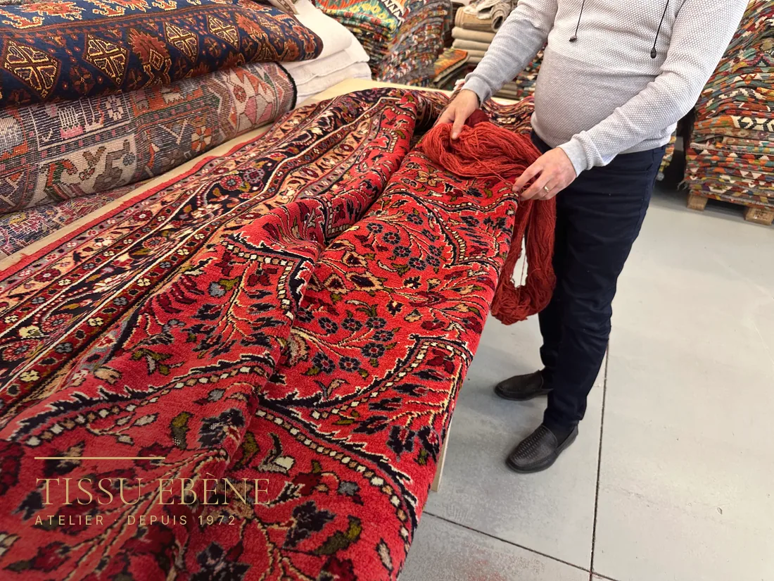 Expert de Tissu Ébène comparant les laines d&rsquo;un tapis à Paris, parmi les pièces de l&rsquo;atelier