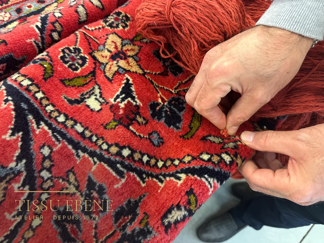 Expert écartant le velours d&rsquo;un tapis persan pour observer le nœud à la base des brins