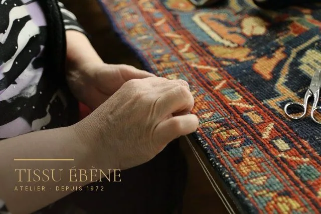 Artisane suivant le bord d&rsquo;un tapis ancien pour repérer la partie de lisière à reprendre